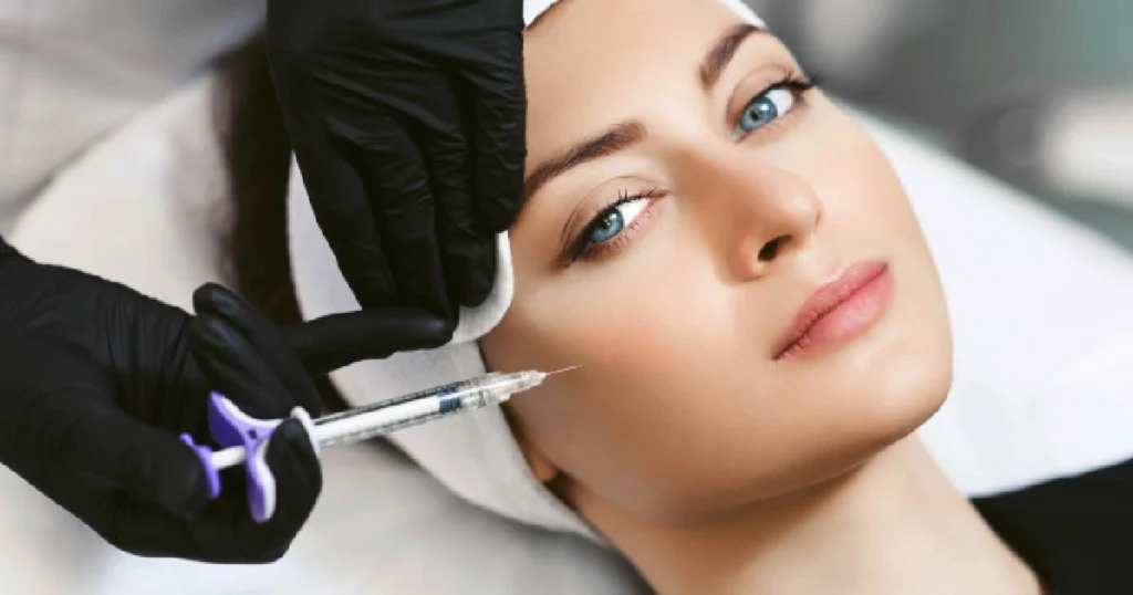 Young woman receiving Botox injection near the eye area by a professional wearing black gloves in a clinical setting in Palm Springs, CA.