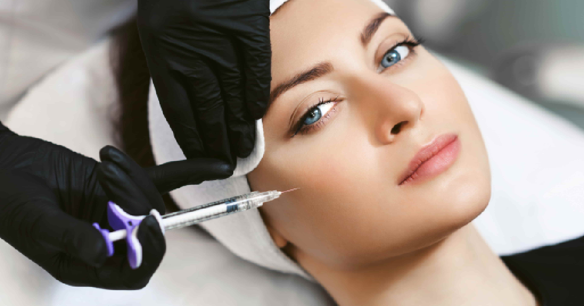Young woman receiving Botox injection near the eye area by a professional wearing black gloves in a clinical setting in Palm Springs, CA.